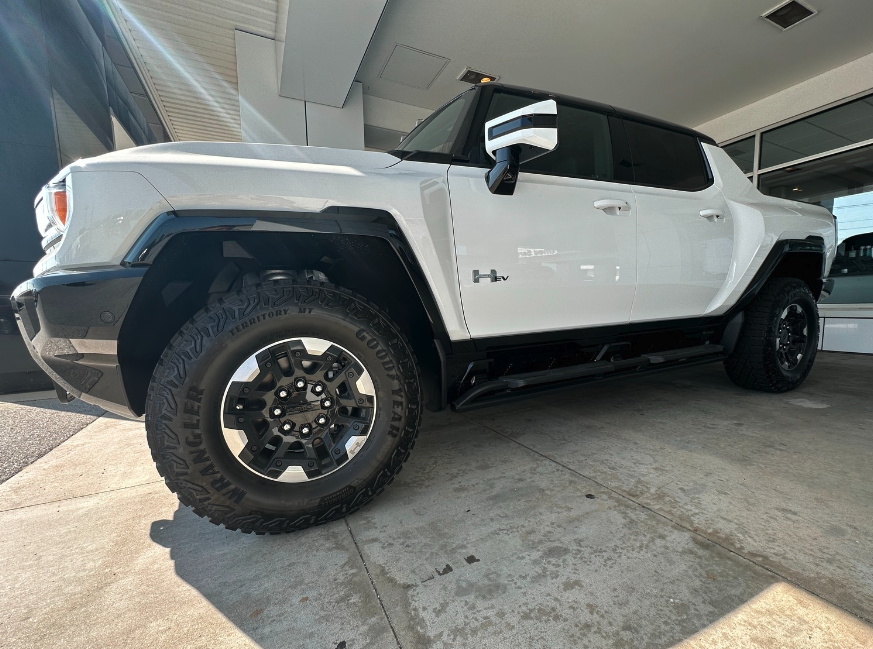 Low-angle side view of a white GMC Hummer EV parked at Crain Buick GMC in Springdale, Arkansas